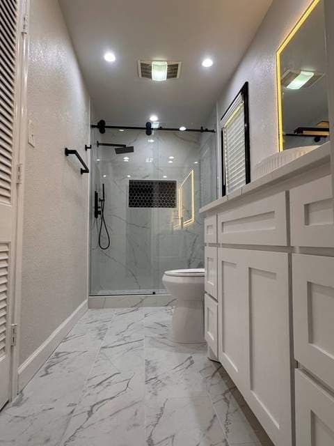 Completed primary bathroom with walk-in shower, white vanity, and illuminated mirror.