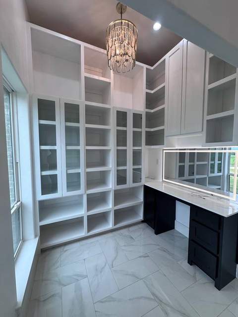 Completed custom dressing room with glass-front cabinetry, open shelving, and vanity.