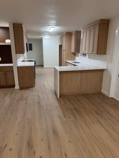 Completed kitchen reconstruction showing cabinetry, surfaces, lighting, and adjoining finish work.